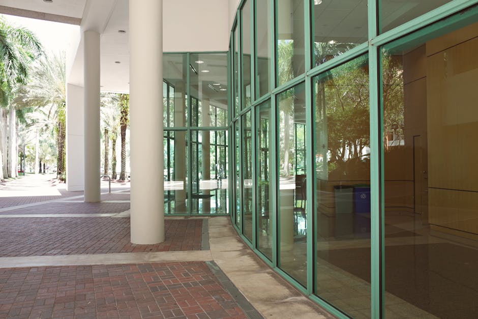 Modern university campus in Coral Gables, Florida, featuring sleek green glass architecture and palm-lined pathways.